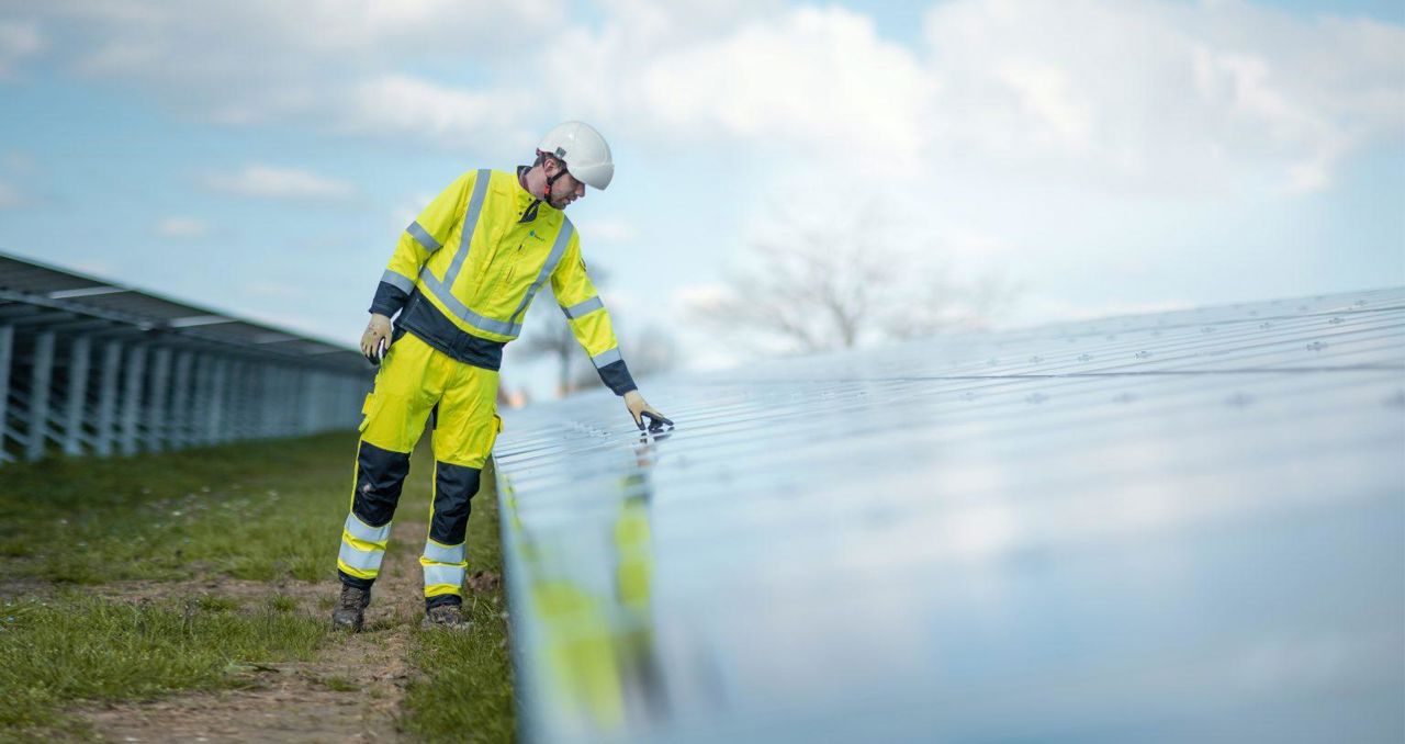 Worker in PPE leaning over solar panel