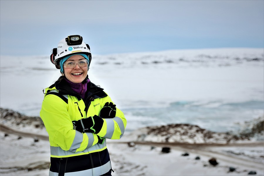 Female Statkraft colleague in full PPE smiling on snowy mountain