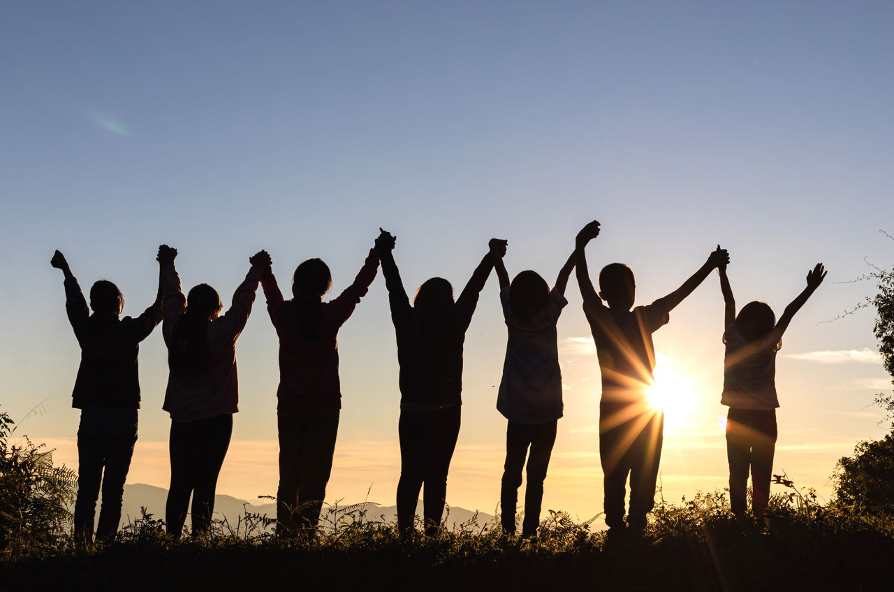 People holding hands in the air at sunset