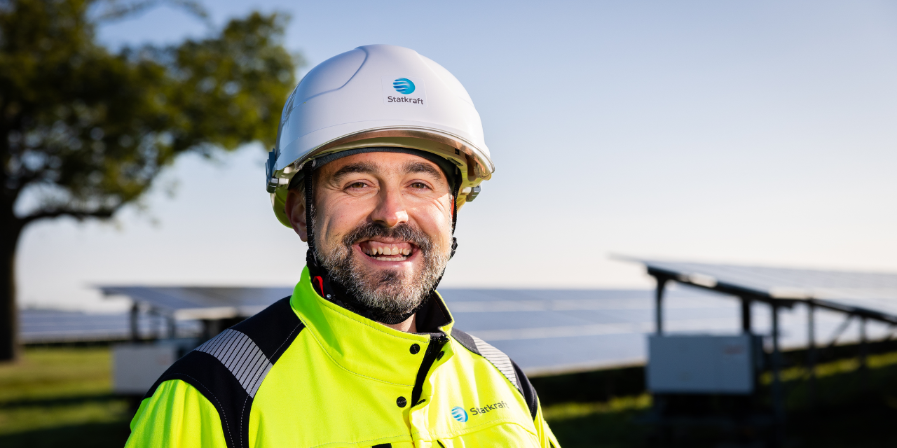 Statkraft colleague in full PPE smiling in front of solar farm