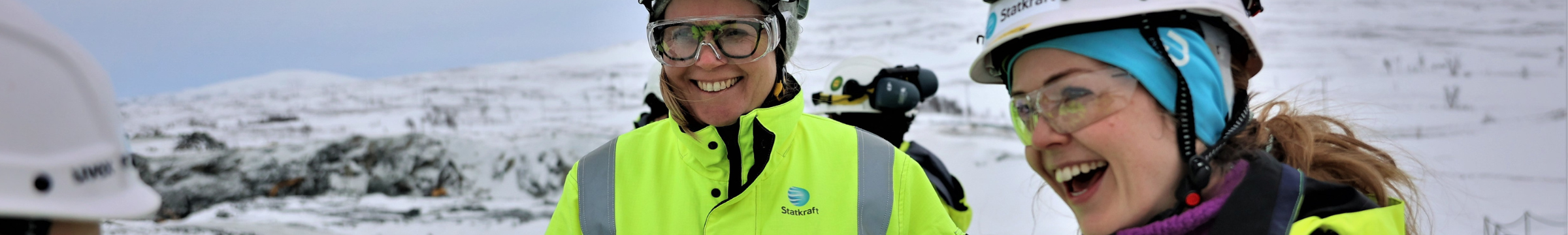 Two female Statkraft workers in PPE with snow mountain landscape in background 